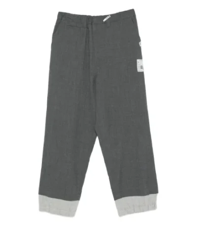 Front view of Maison Mihara Yasuhiro Cuffed Panelled Trousers with structured panel design