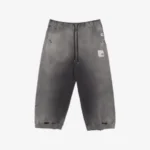 Front view of distressed track pants featuring bold logo-print detailing