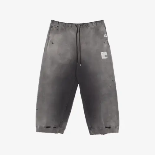 Front view of distressed track pants featuring bold logo-print detailing